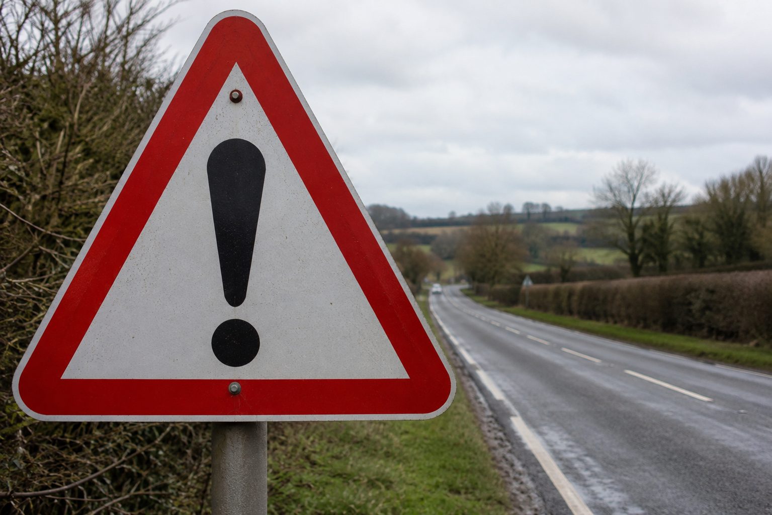 A warning sign next to a long road